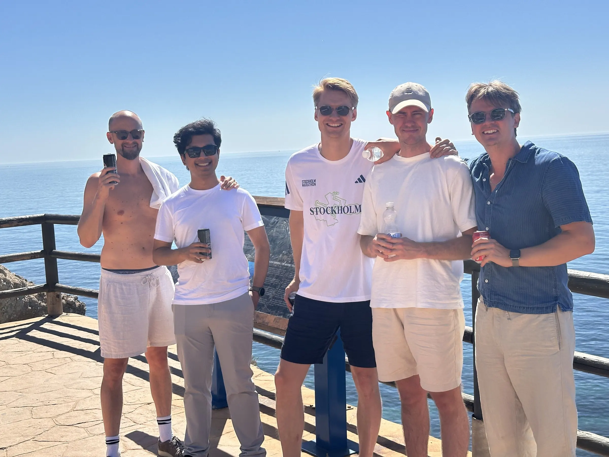Fem kollegor på ett utsiktsdäck vid havet en solig dag på kickoffen i Málaga.